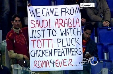 مشجعون سعوديون يرفعون لافتة &#8220;أتينا من المملكة لمشاهدة توتي وهو &#8220;ينتف&#8221; ريش الدجاج&#8221;