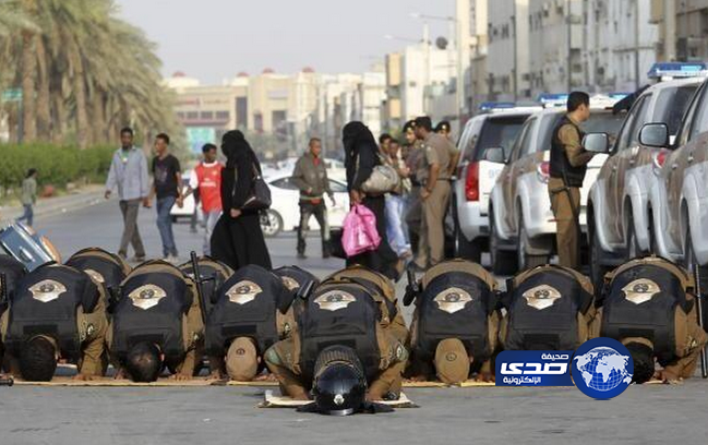رجال أمن يؤدون الصلاة أثناء عملهم في مواجهة أحداث شغب أحدثتها عمالة مخالفة في منفوحة