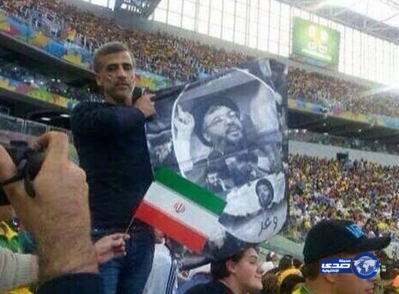 أحد مشجعي المنتخب الايراني من أرض الملعب يحمل صورة لحسن نصر الله