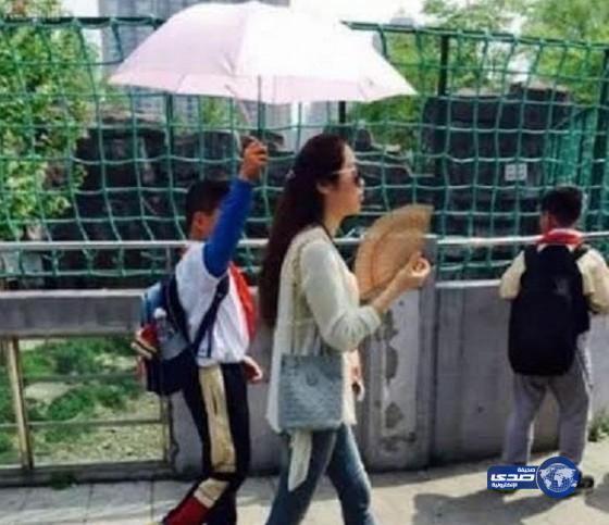 طالب صيني يمسك بمظلة لمعلمته تثير غضباً على شبكات التواصل