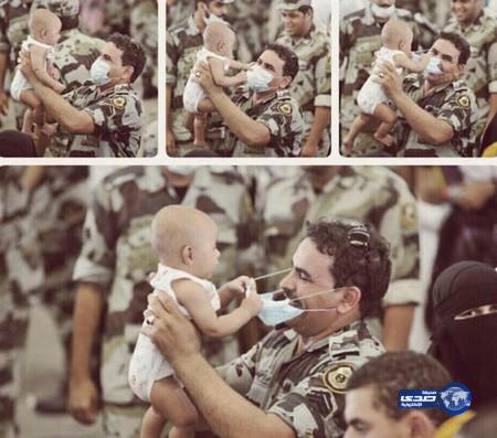 رجل أمن قوات الطوارئ يحمل طفلاً ويلهو معه