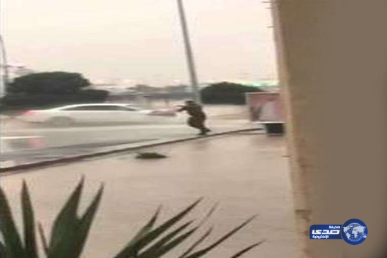 شاهد .. رجل أمن يرفع صورة ولي العهد بعد سقوطها بسبب الأمطار