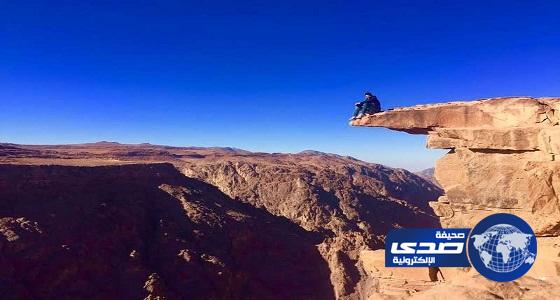 بالصور.. شاب سعودي يغامر بحياته ويقف على حافة صخرة فوق ارتفاع 1050 متر