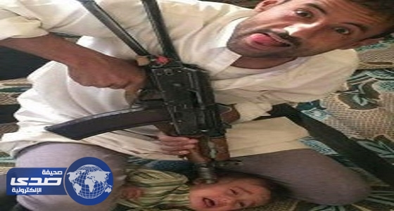 صورة صادمة ليمني يهدد رضيع بسلاح ألي