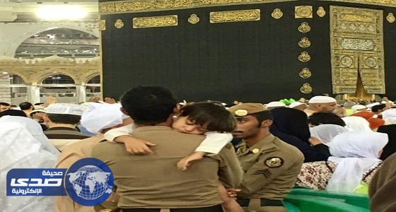 بالصور.. رجل أمن يحمل طفلا «تائها» في صحن المطاف