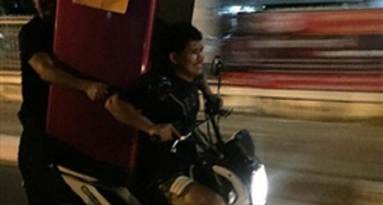 بالصور.. رجلان ينقلان ثلاجة ضخمة على دراجة نارية