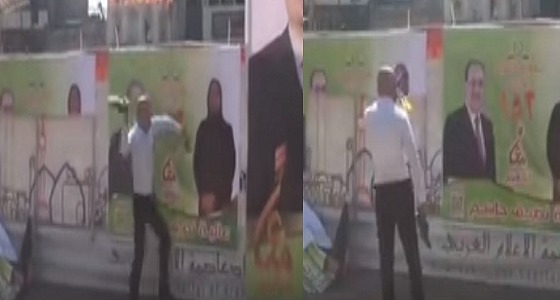 بالفيديو.. عراقي يضرب لافتات المالكي وعلاوي بالأحذية