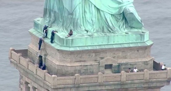 بالفيديو.. إمرأة تتسلق تمثال الحرية بنيويورك والشرطة تحاول إنقاذها