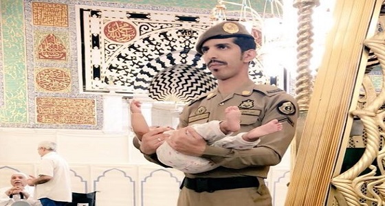 صورة تجسد الإنسانية.. عسكري يحمل طفلا ليتمكن والده من الصلاة بالمسجد النبوي