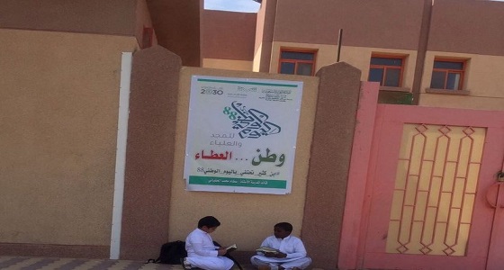صورة.. طالبان يستغلان الانتظار خارج المدرسة بقراءة القرآن في الأفلاج