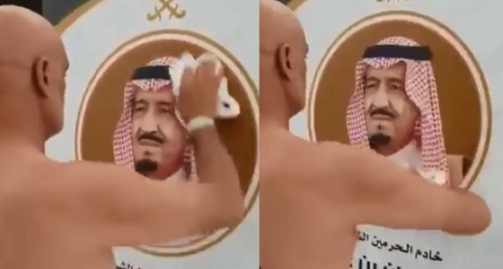 بالفيديو.. حاج يزيل آثار المطر عن صورة خادم الحرمين