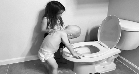 قصة الصورة المؤلمة لطفل السرطان الواقف أمام المرحاض بمساعدة أخته
