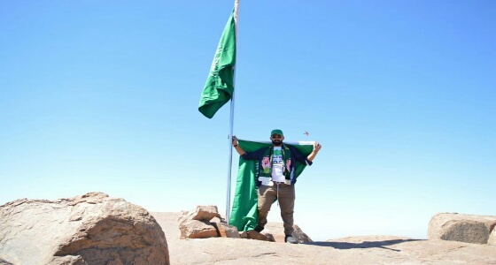 بالصور.. مواطن يرفع علم المملكة بأعلى قمة جبل اللوز