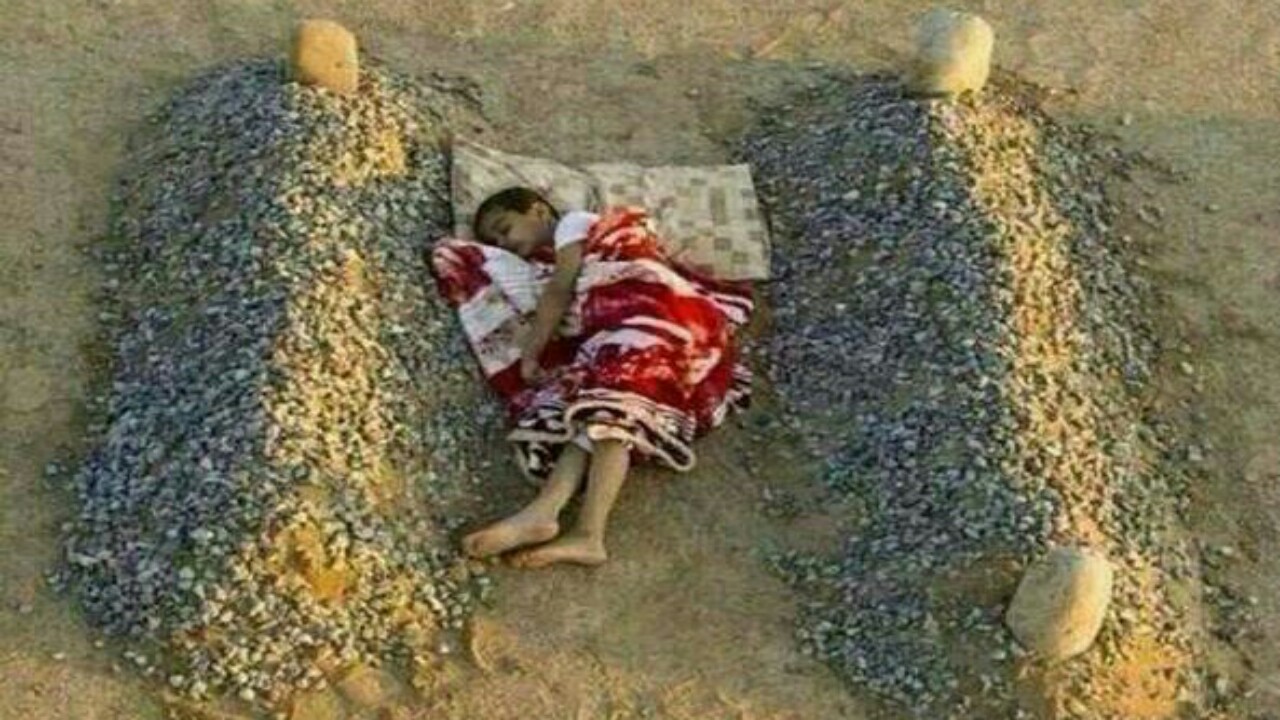 حقيقة صورة الطفل النائم بين قبري والديه 