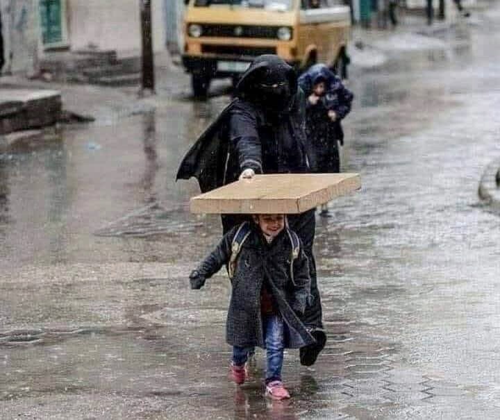 صورة جميلة لأم تحنو على طفلها تحت المطر