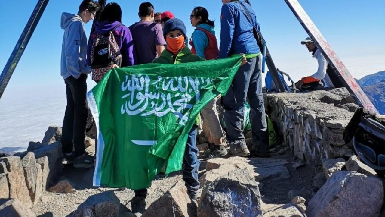 بالصور.. طفل يرفع علم المملكة في أعلى قمة جبل بالوطن العربي