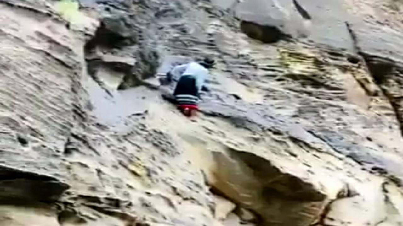 شاهد.. مرشد سياحي يتسلق جبال صخرية بجازان حافي القدمين