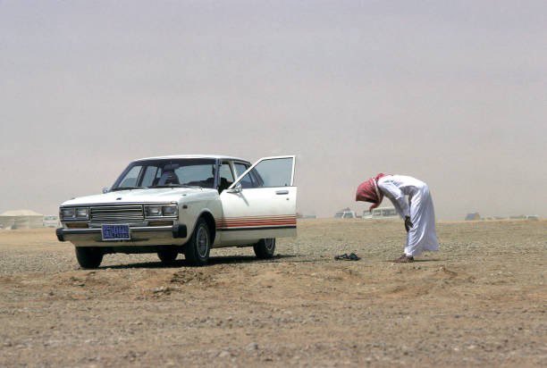 رجل يصلي بجانب سيارته في الرياض