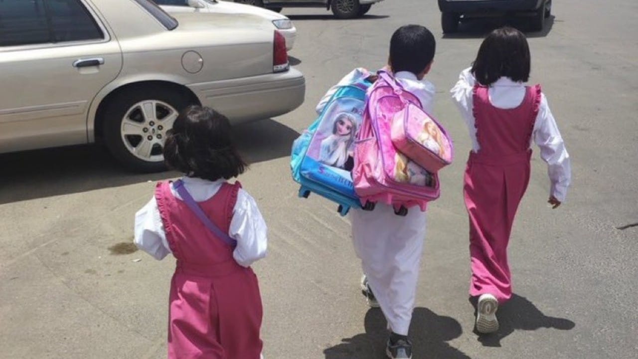 صورة مؤثرة لطفل يحمل حقائب أختيه أثناء ذهابهم للمدرسة