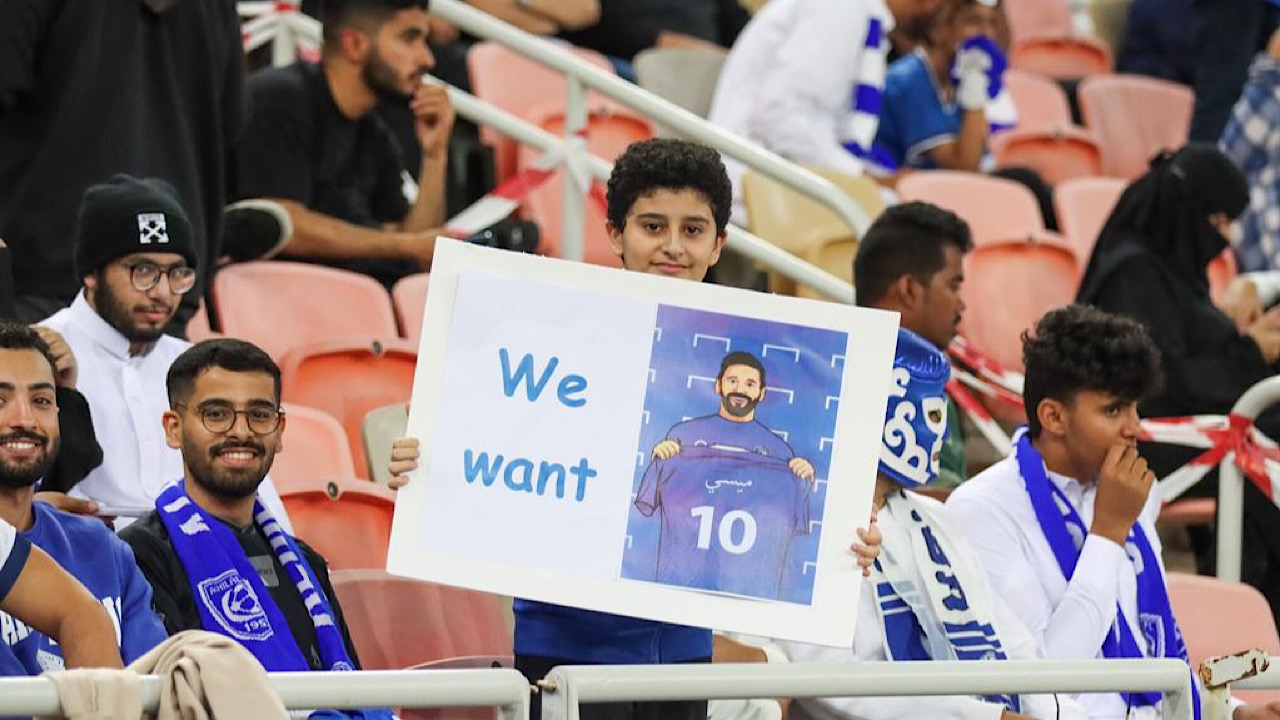 مشجع هلالي يرفع لافتة مكتوب عليها “نحن نريد ميسي” خلال مباراة الهلال والاتحاد