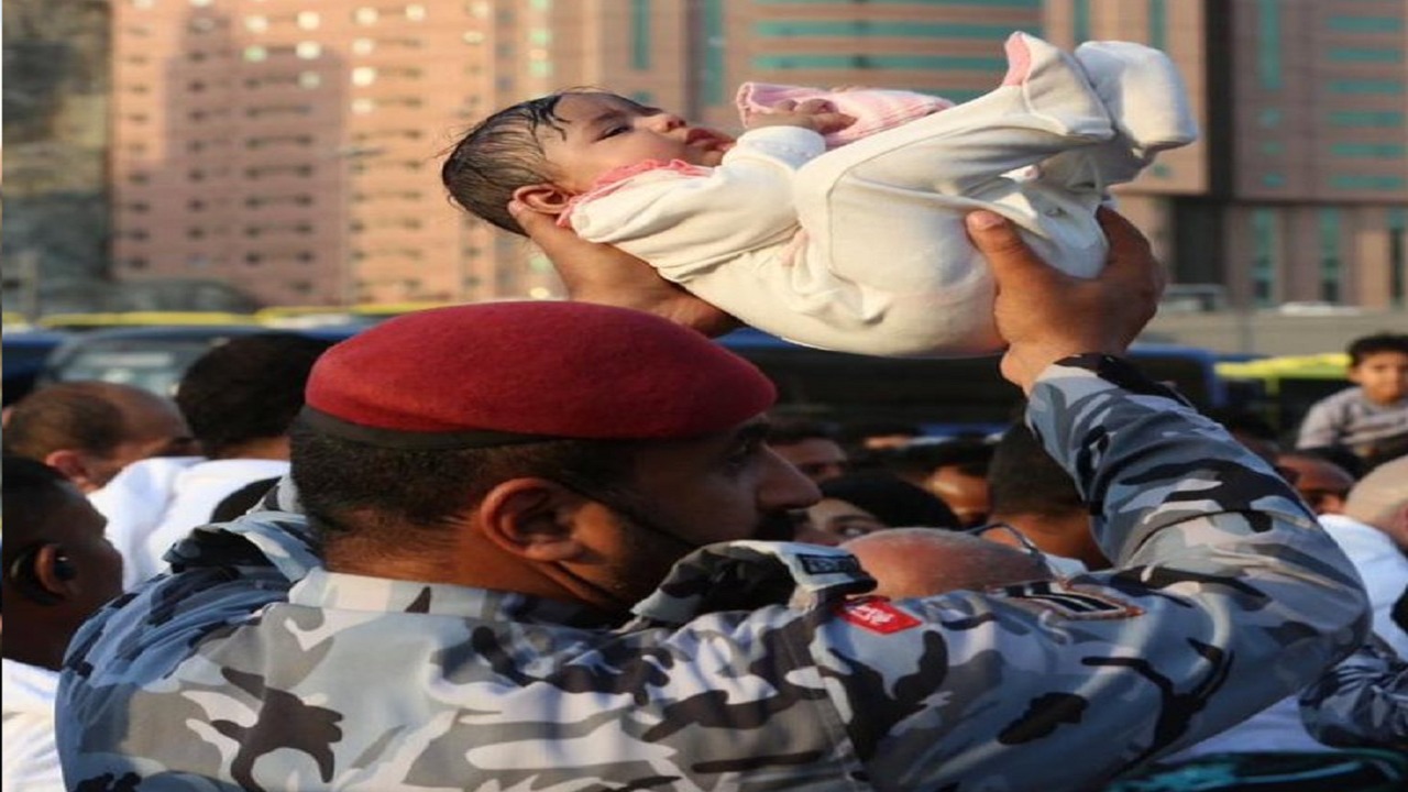 رجل أمن يخطف الأنظار بحمله طفل رضيع  وسط زحام الحرم المكي