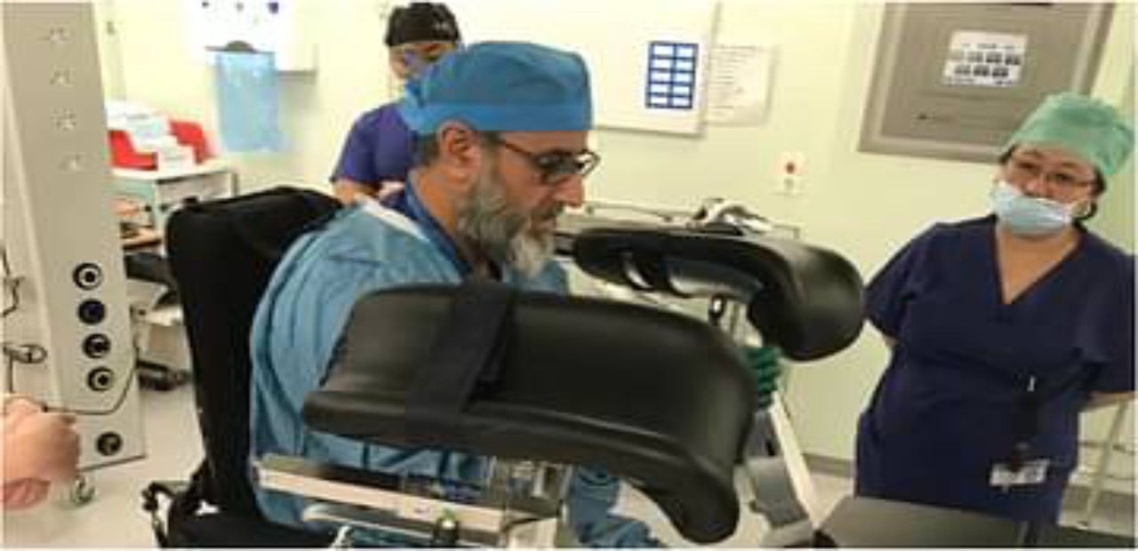 في حدث نادر.. طبيب يجري عملية جراحية من كرسيه المتحرك بعد إصابته بالشلل