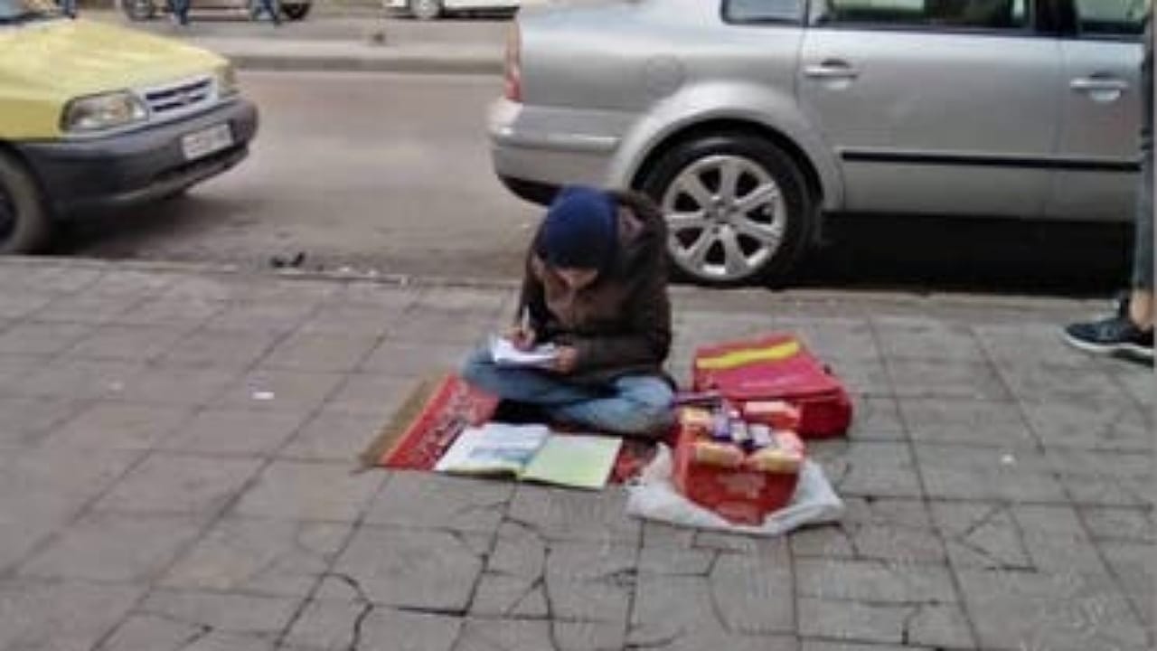 صورة لطفلة سورية تدرس أثناء بيعها الحلوى في الشارع